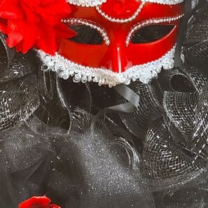 Wreath black with red roses. Mysterious red mask.